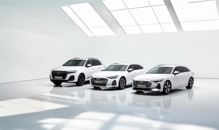 Drei weiße Audi Modelle – ein Audi A5, ein Audi A6 und ein Audi Q7 – in einem puristischen, lichtdurchfluteten Ausstellungsraum.