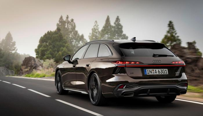 Der neue Audi A6 Avant auf einer einsamen Landstraße. Zu sehen sind das Fahrzeugheck mit individueller Rücklichtsignatur und die Fahrerseite.