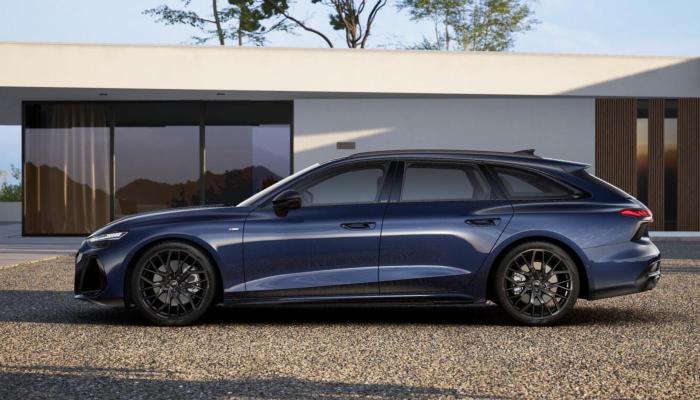 Seitenansicht des neuen Audi A6 Avant. Das Fahrzeug steht auf einer Kiesfläche vor einem modernen Wohngebäude.