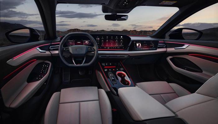 Blick von hinten auf das Cockpit des Audi A6 Avant. Zu sehen sind unter anderem das optionale Doppelspeichen-Sportlederlenkrad, das Panoramadisplay und das optionale Beifahrerdisplay.