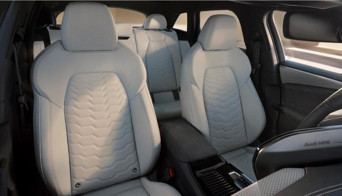 Blick von links vorne ins Innere eines Audi A6 e-tron Modells. Im Fokus stehen die vorderen Sitze mit einem Leder-/Kunstleder-Bezug in elegantem Beige.