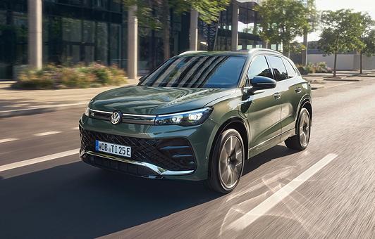 Der Tiguan eHybrid in Cipressino-Grün Metallic fährt auf einer Straße