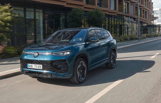 Der Tayron eHybrid in Nightshade Blue Metallic fährt auf einer Straße