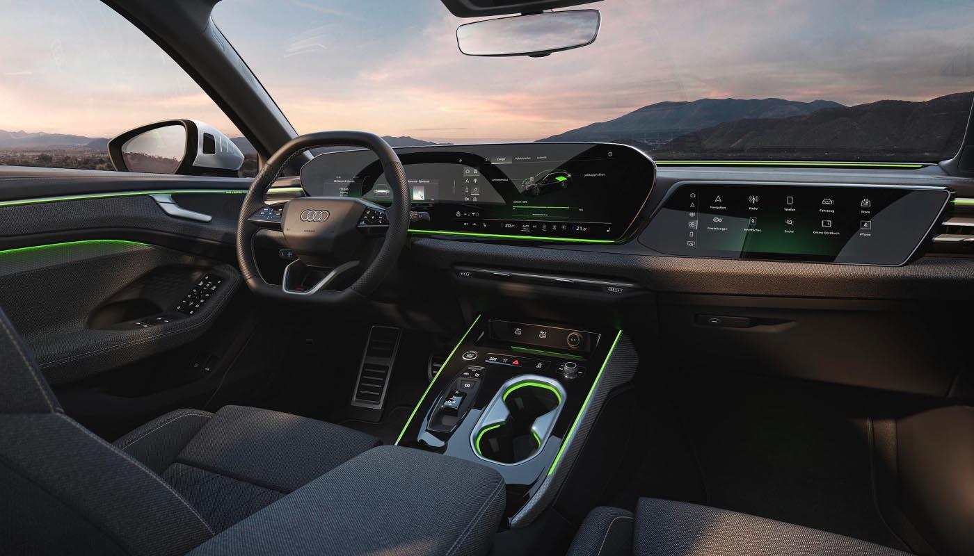 Das Cockpit des Audi A6 Avant mit LED-Lichtbändern in Grün. Im Fokus: die Mittelkonsole, das Lederlenkrad, das Panoramadisplay und das Beifahrerdisplay.