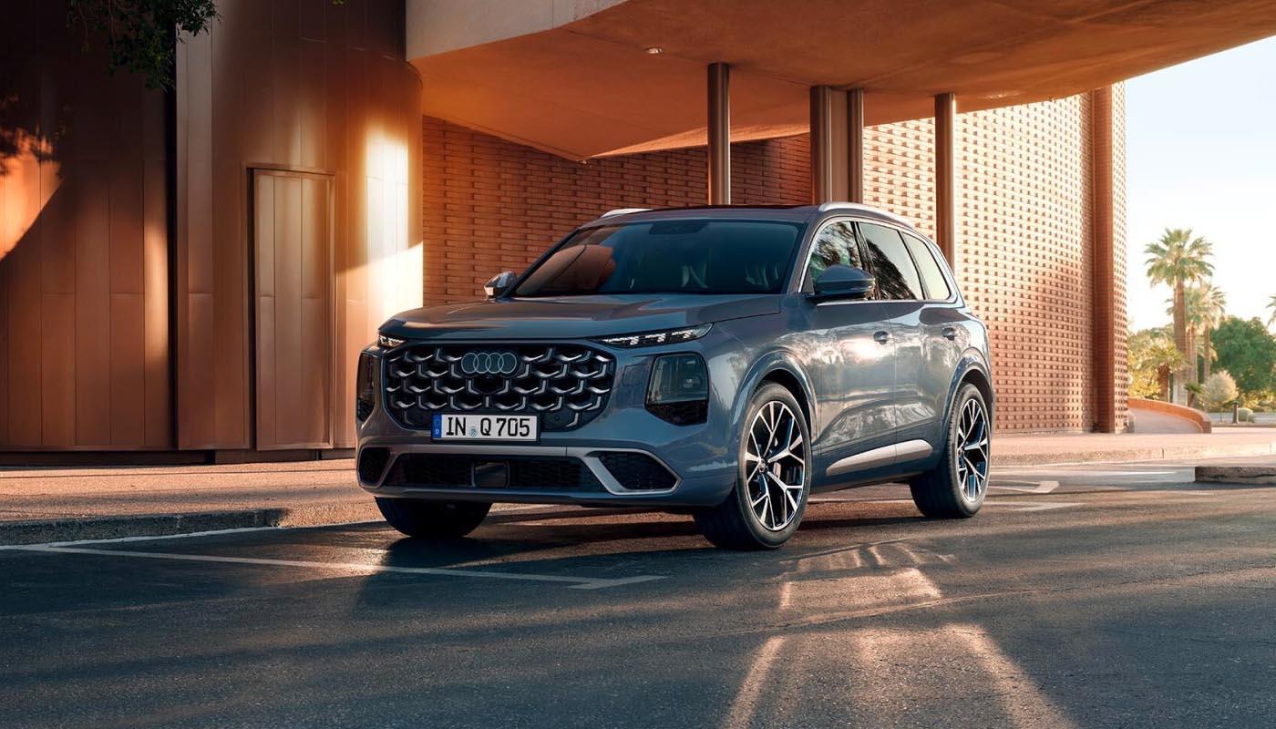 Der neue Audi Q7 in Dreiviertelansicht vor moderner Architektur im warmen Licht der Abendsonne.